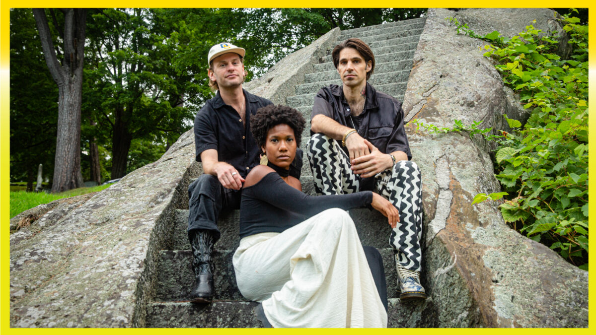 Three people sitting on stone steps looking at the camera.