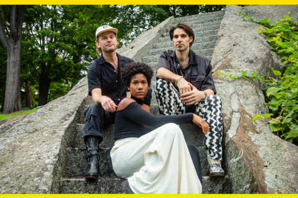 Three people sitting on stone steps looking at the camera.