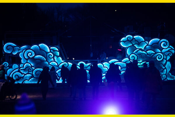 A bus in the dark covered in lights that are shaped like clouds.