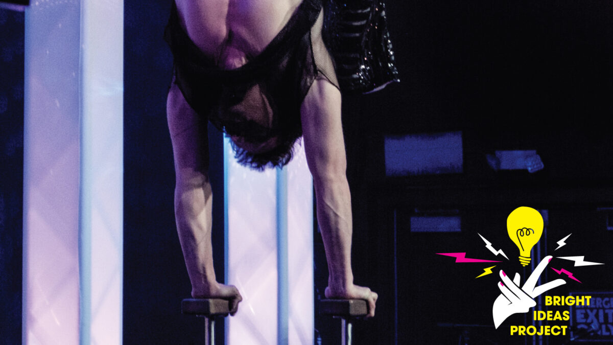 Photo of a Wabaam performance, where a man is executing a handstand on props.