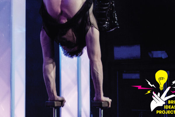 Photo of a Wabaam performance, where a man is executing a handstand on props.